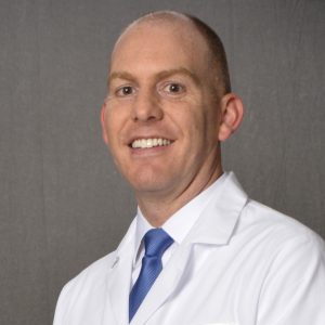 white male physician in lab coat and blue neck tie