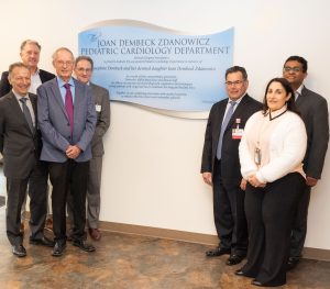 group of 7 people standing in front of plaque