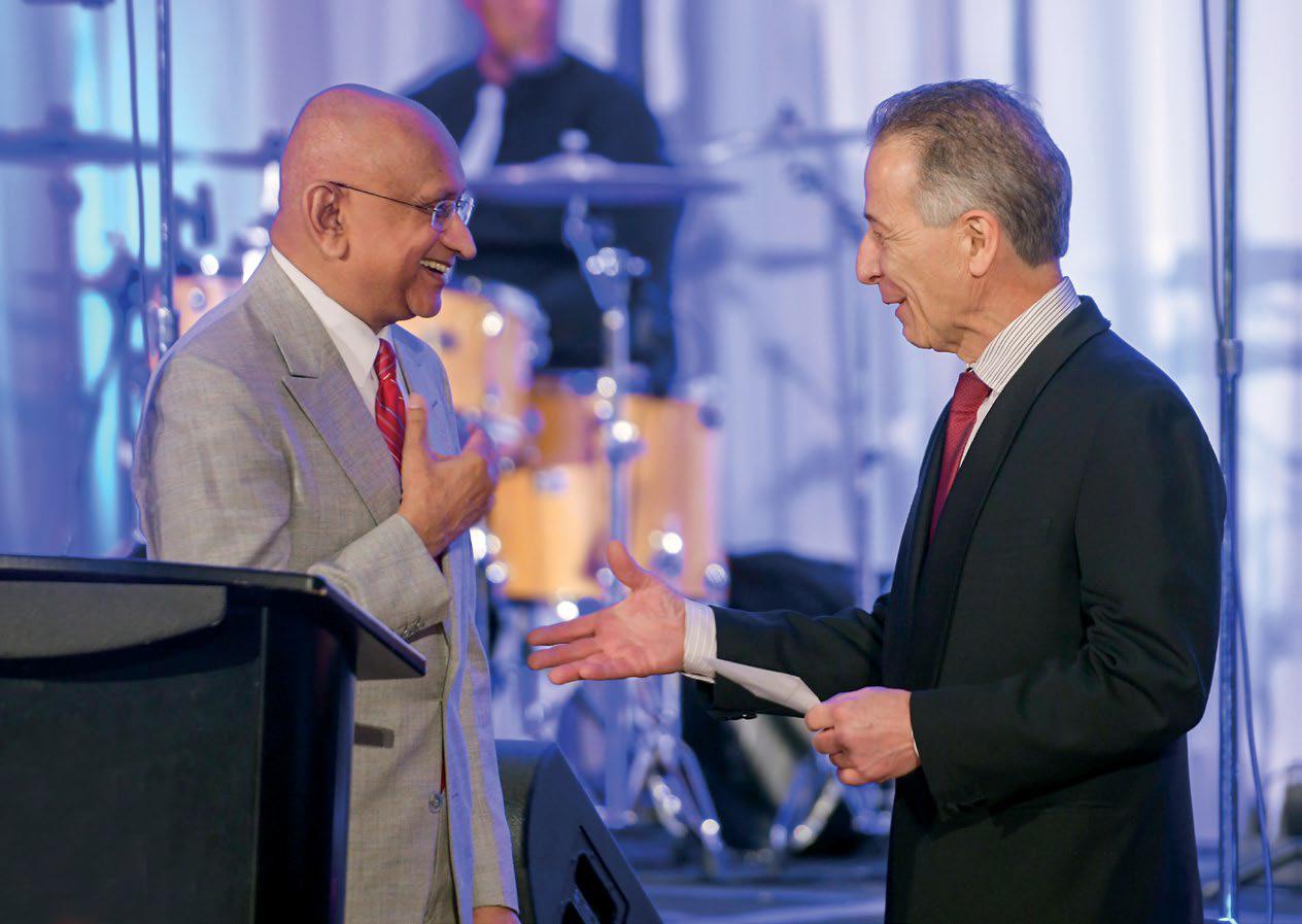 two men shaking hands while one presents the other with an award