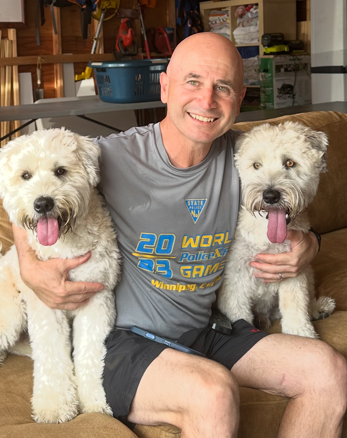 man sits with a dog under each arm