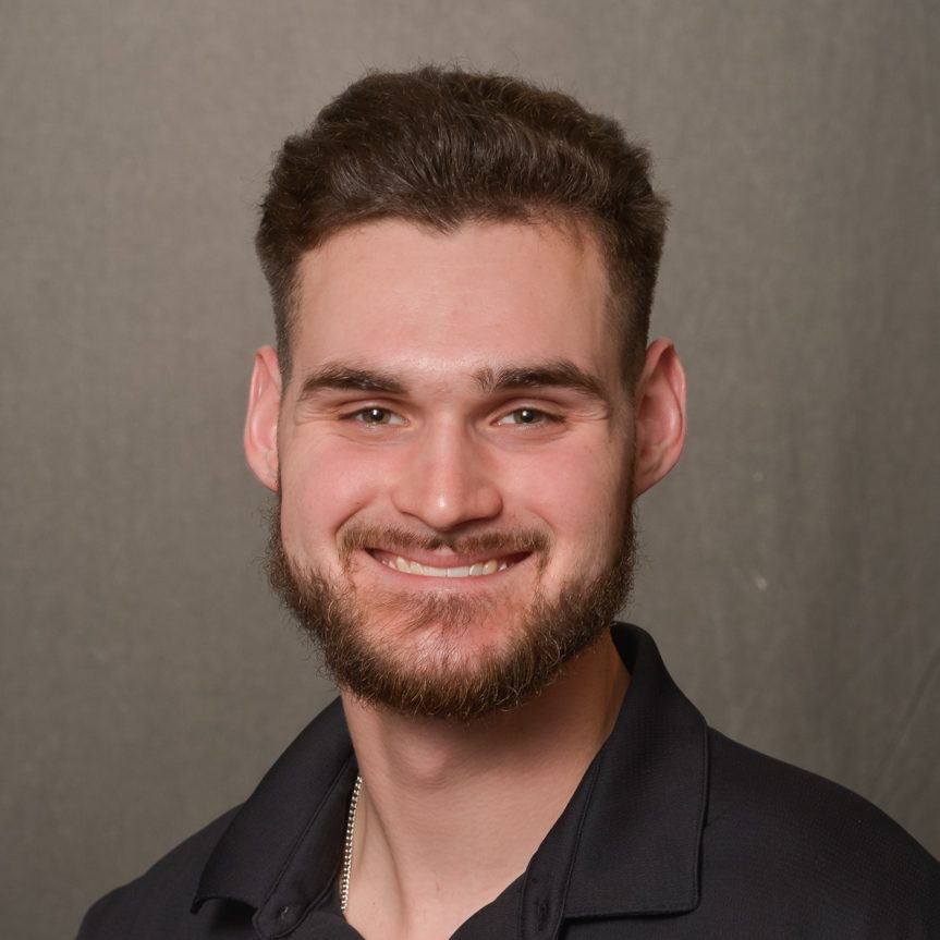 man with brown hair wearing black polo shirt